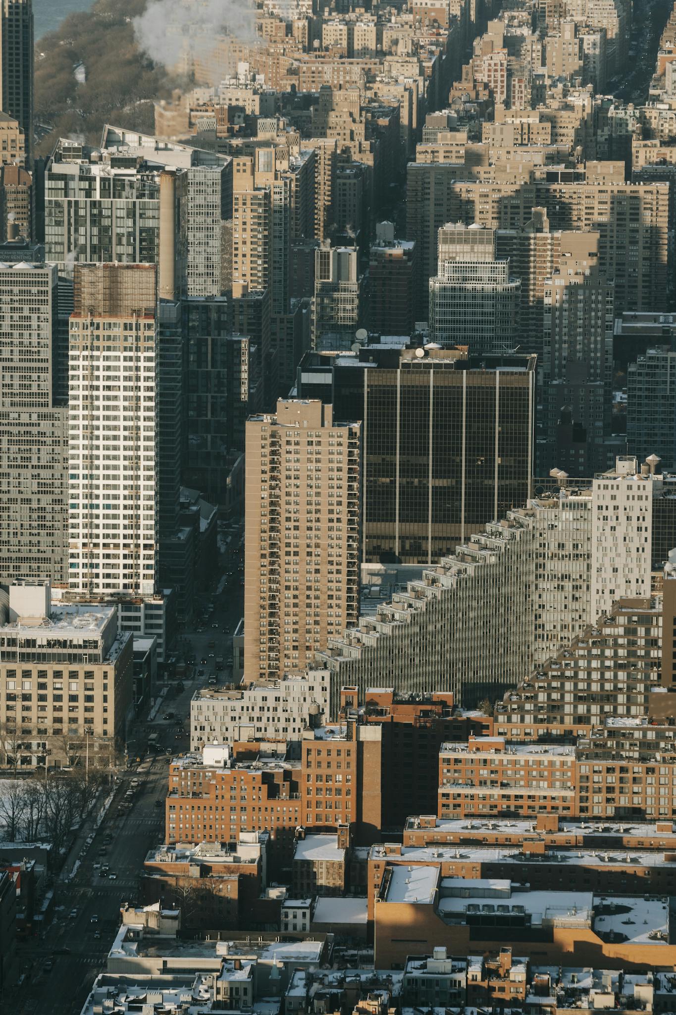 Drone view of densely build district of metropolis with high skyscrapers nearby residential buildings in winter day